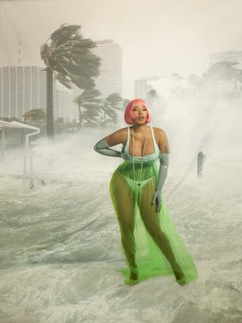 Person in green outfit standing in stormy surf