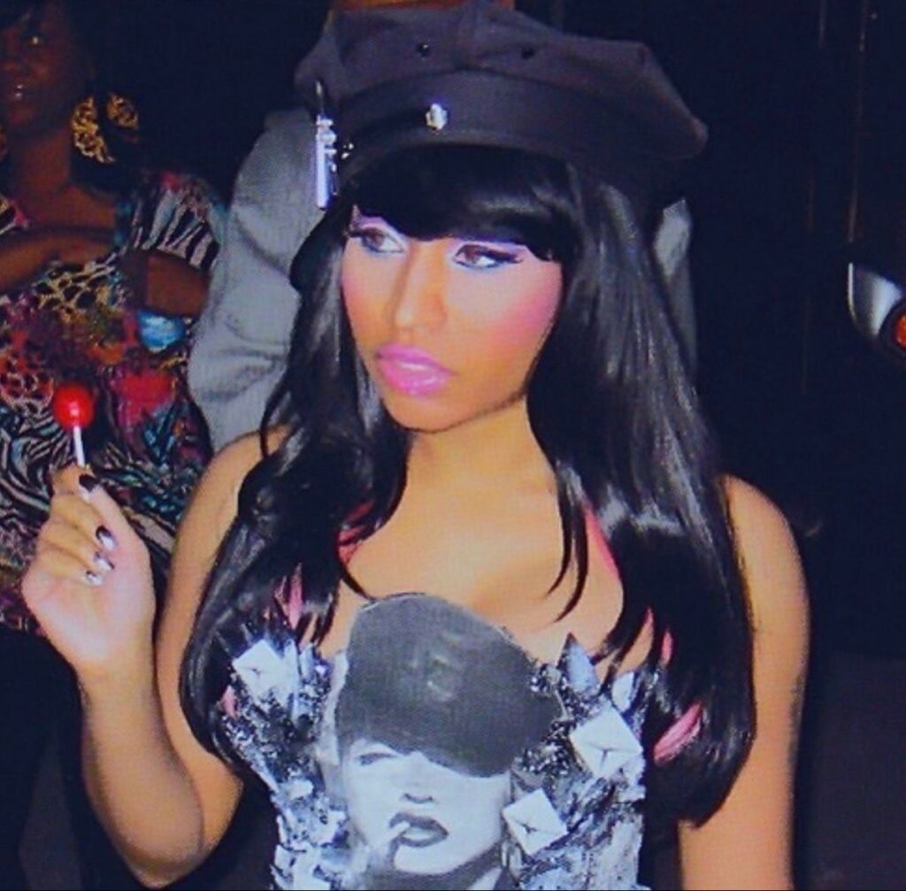 Person wearing black cap holding red lollipop